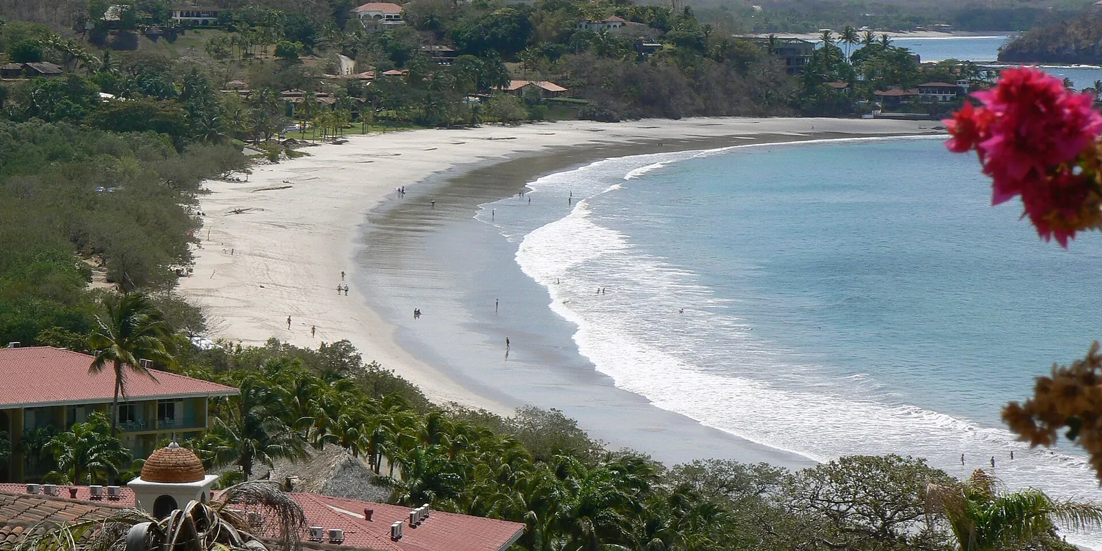A white beach curving below green hills