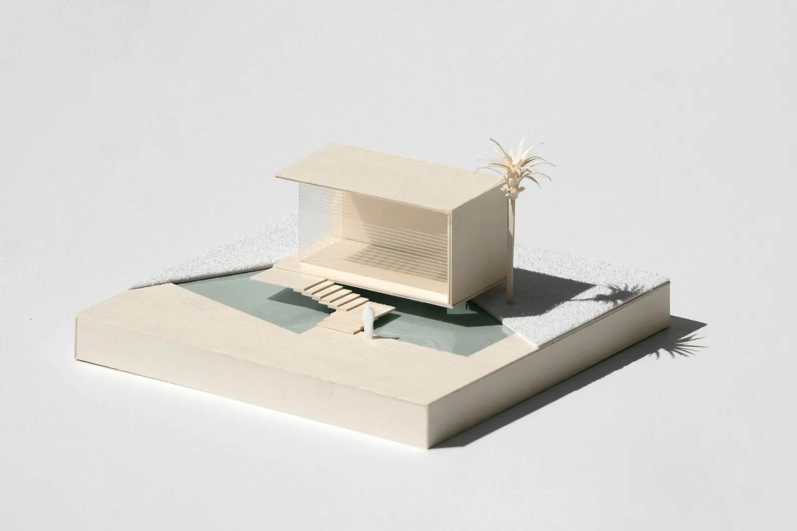 A white card model of a cantilevered house with a palm tree