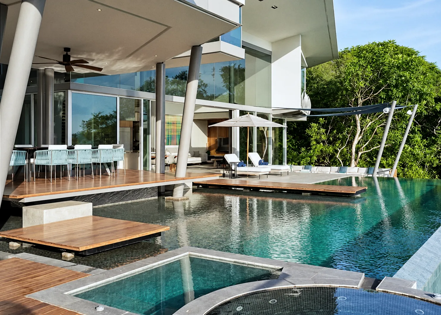 Pool deck under the house, with slanted steel columns, a plunge pool and the infinity edge