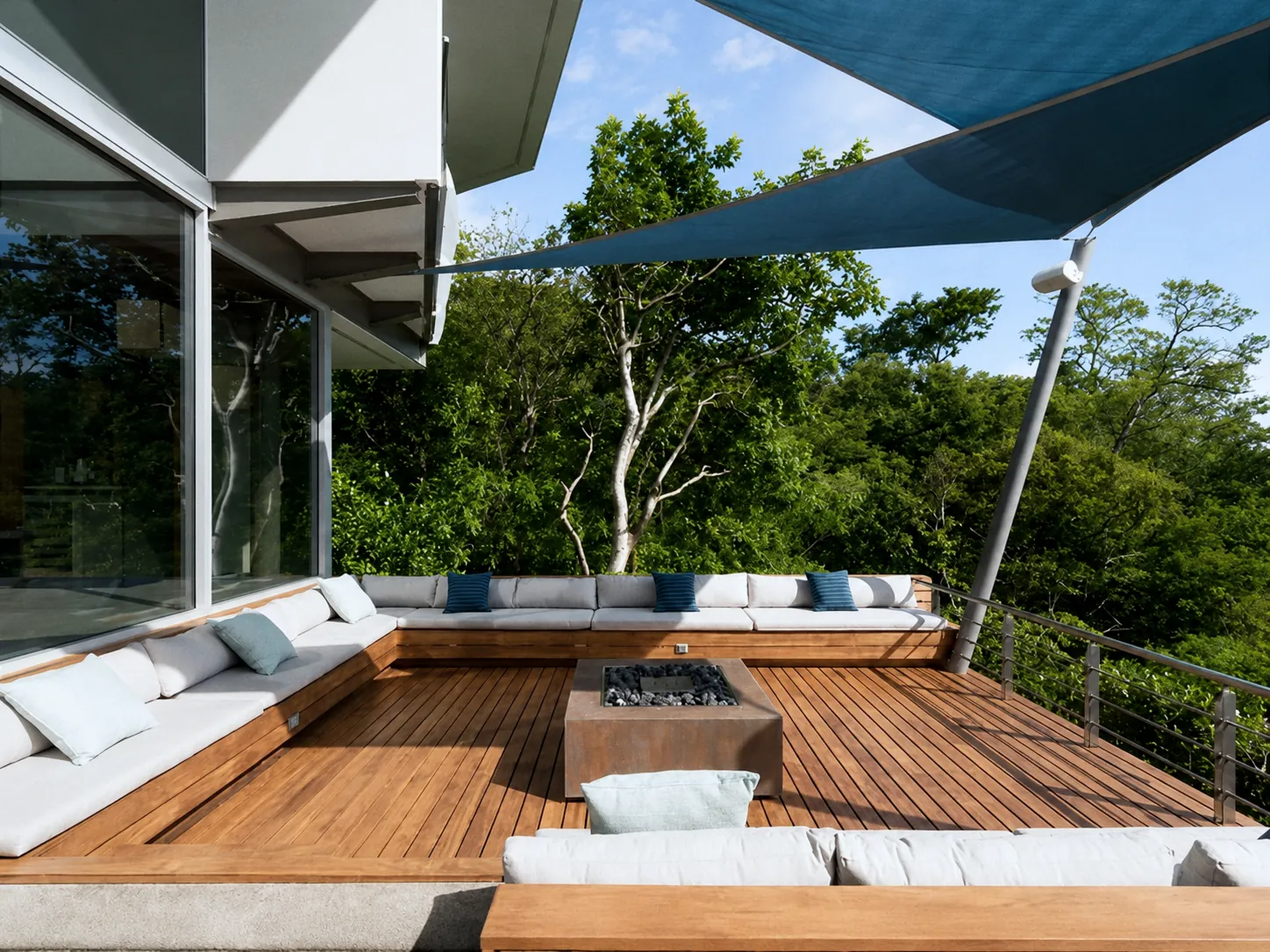 Sunken lounge terrace with built-in sofas and a fire pit under a shade sail